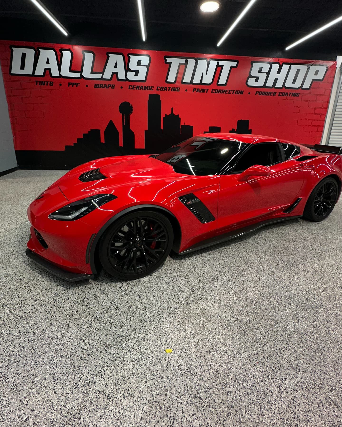 Red Corvette parked under the Dallas Tint Shop storefront sign