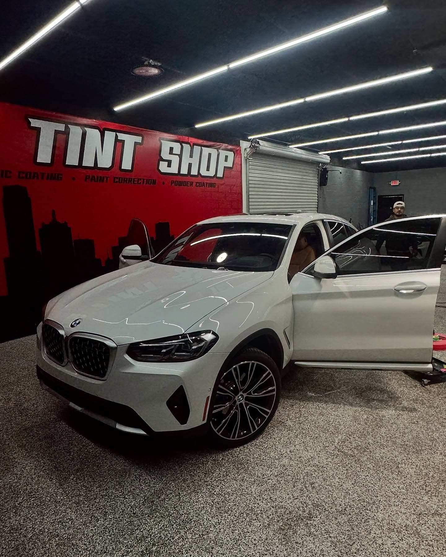 White BMW in the bay beside the Dallas Tint Shop mural