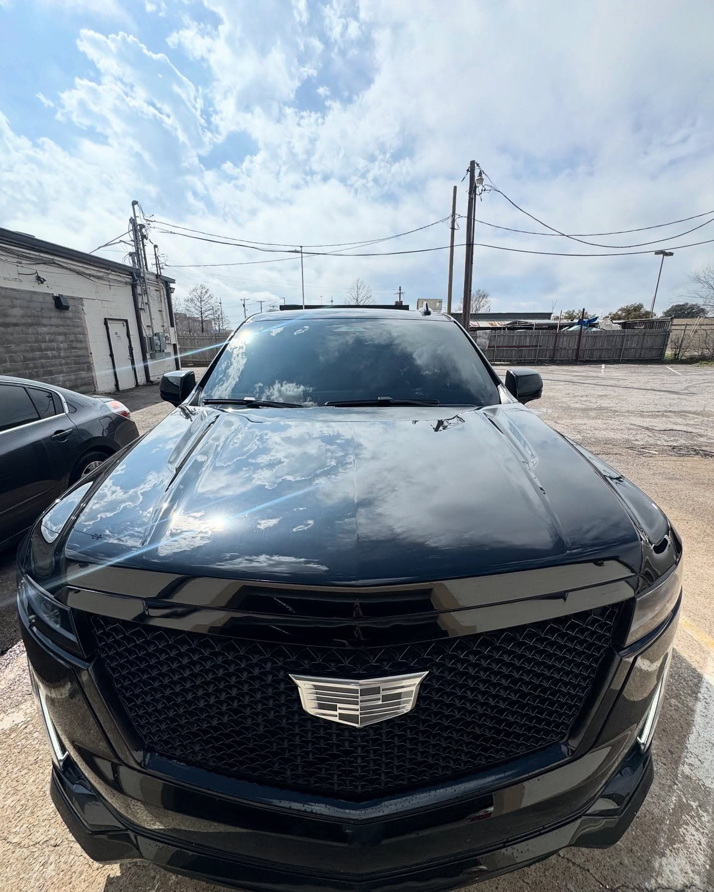 Black Cadillac Escalade with tinted windows outside the shop