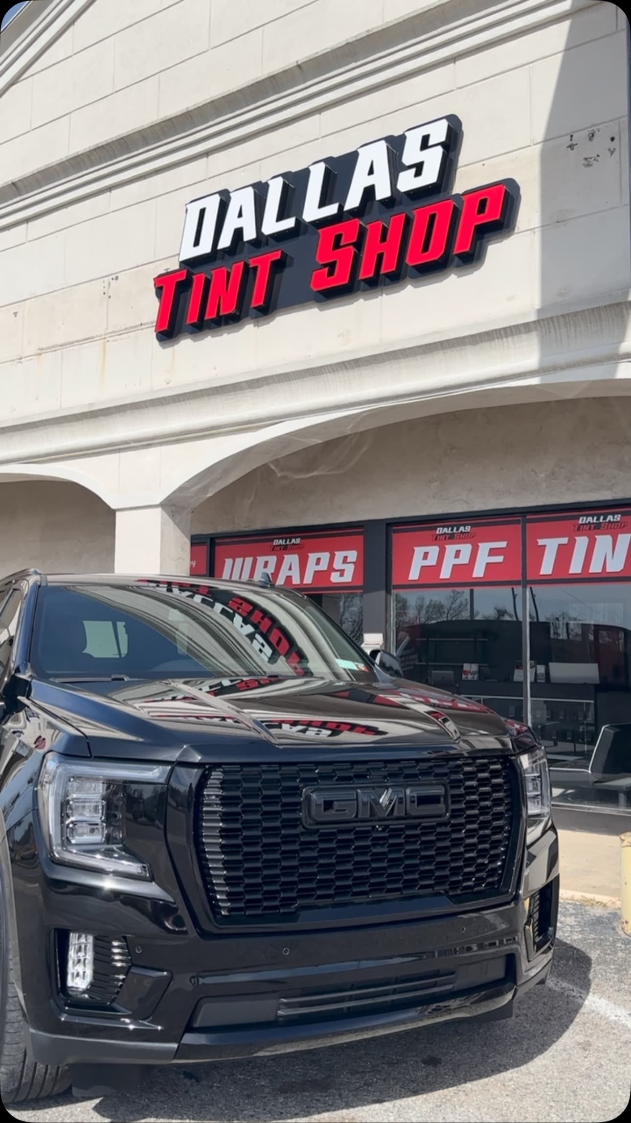 Black GMC Denali after a chrome delete, parked outside the Dallas Tint Shop storefront